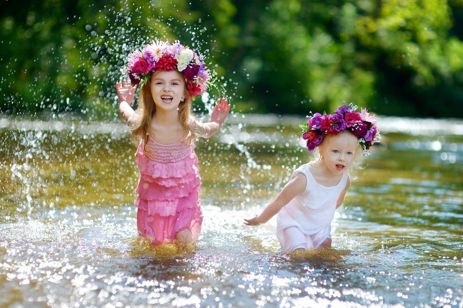 two girls wearing flower crowns splashing in the river