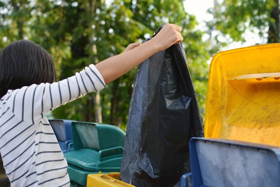 woman emptying garbage bag into trash bins