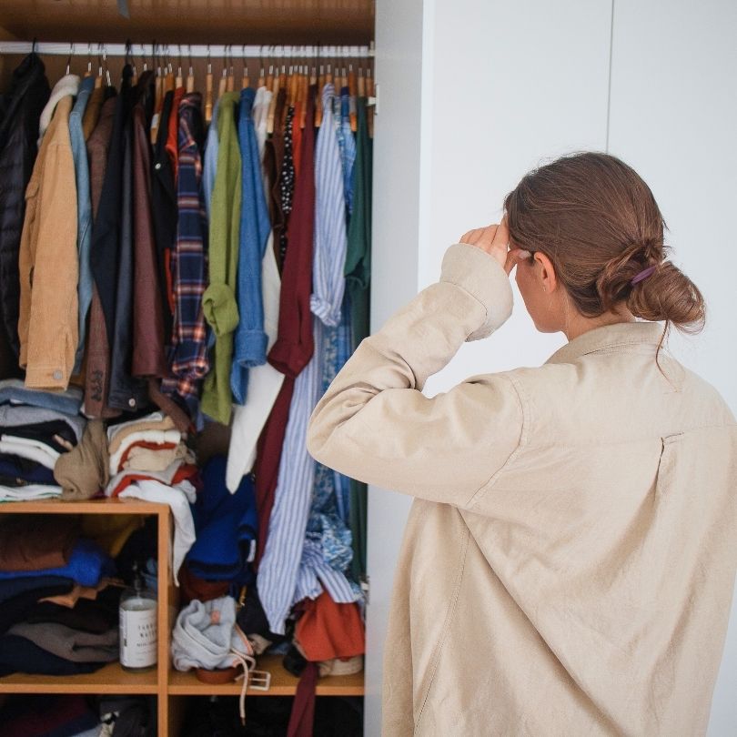 woman standing in front of crowded closet wondering what to wear