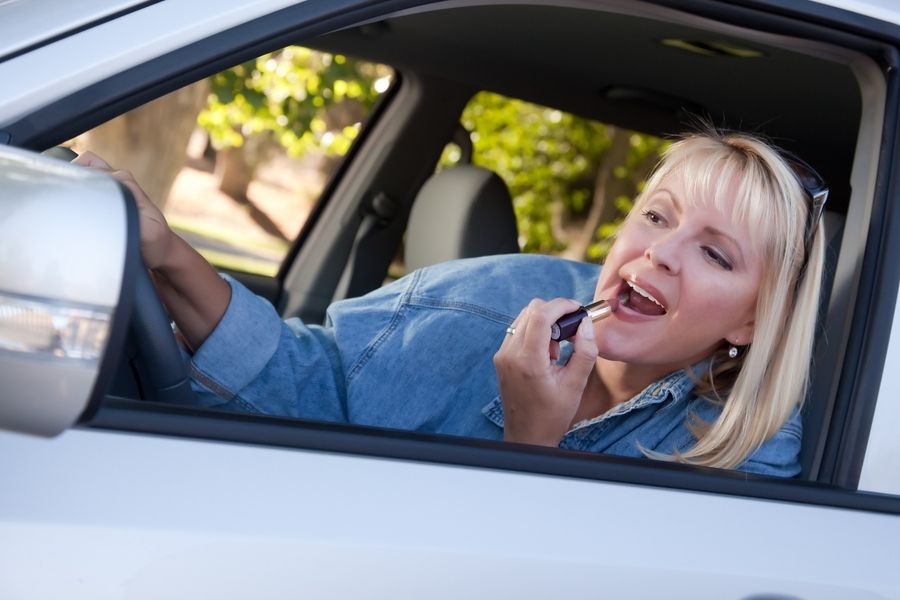 Mom putting on lipstick using car sideview mirror