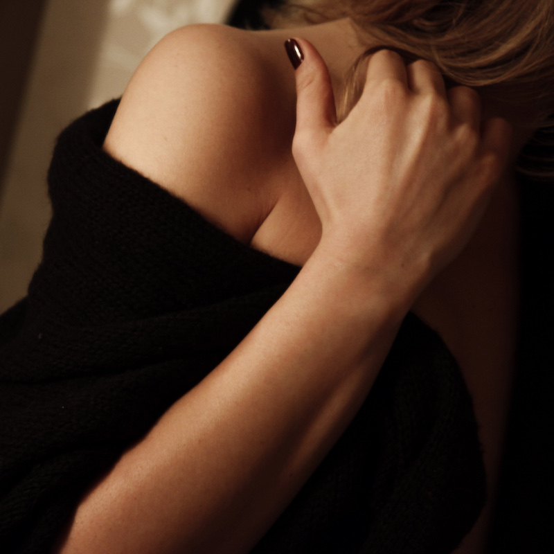 closeup of woman's shoulder and hand wrapped in a black robe