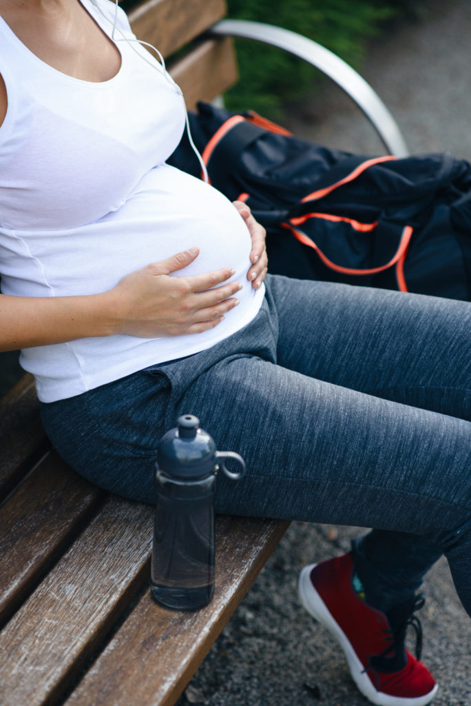 Pregnant woman with Gym Bag on park bench
