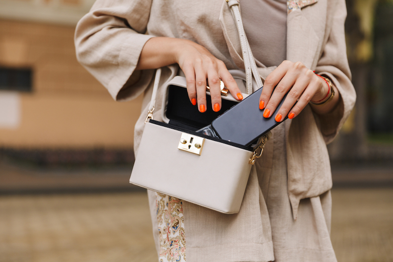 woman putting phone in small bag