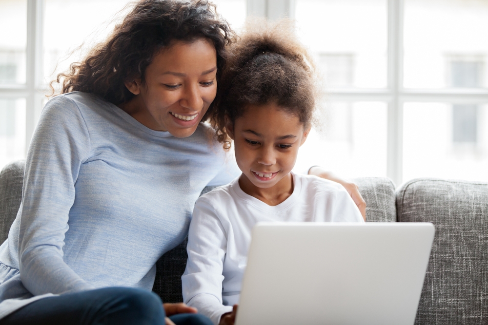Mother in long sleeve blue knit shirt helps daughter at the computer