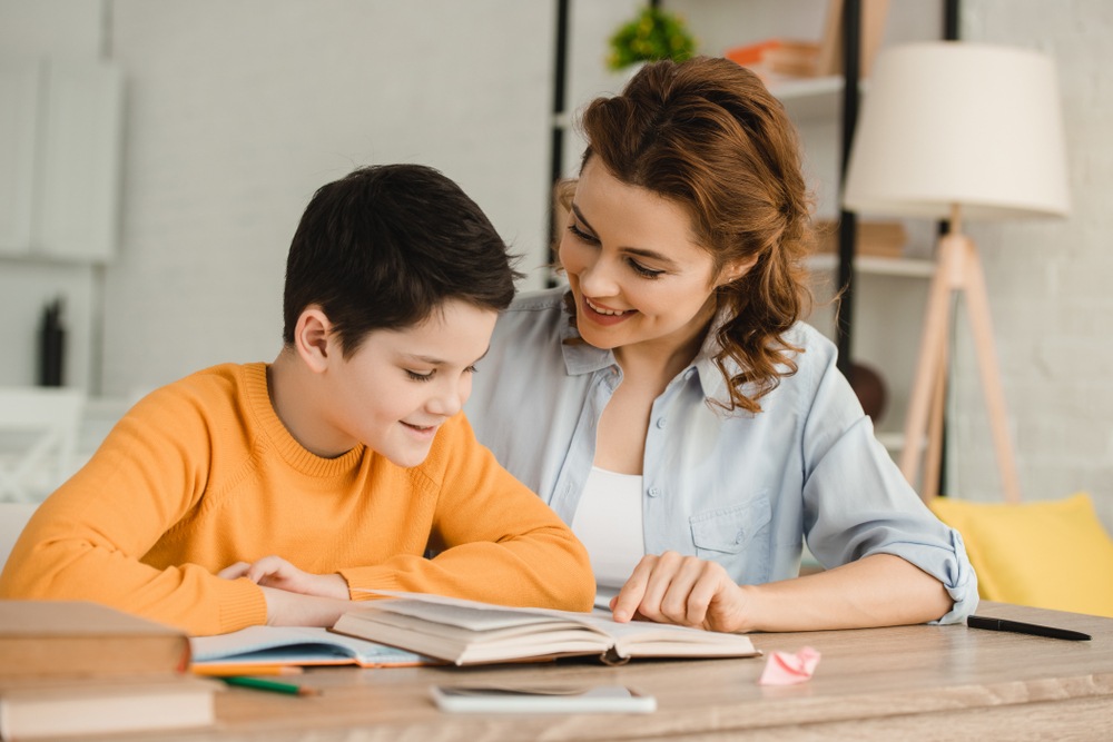Homeschool Style: Mother wearing chambray shirt over white tank top helps son with homework