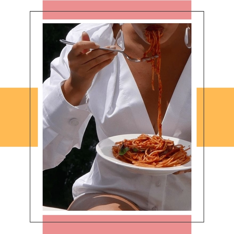 woman in white shirt eating spaghetti in red sauce