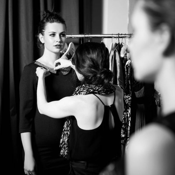 stylist adjusting model's dress collar