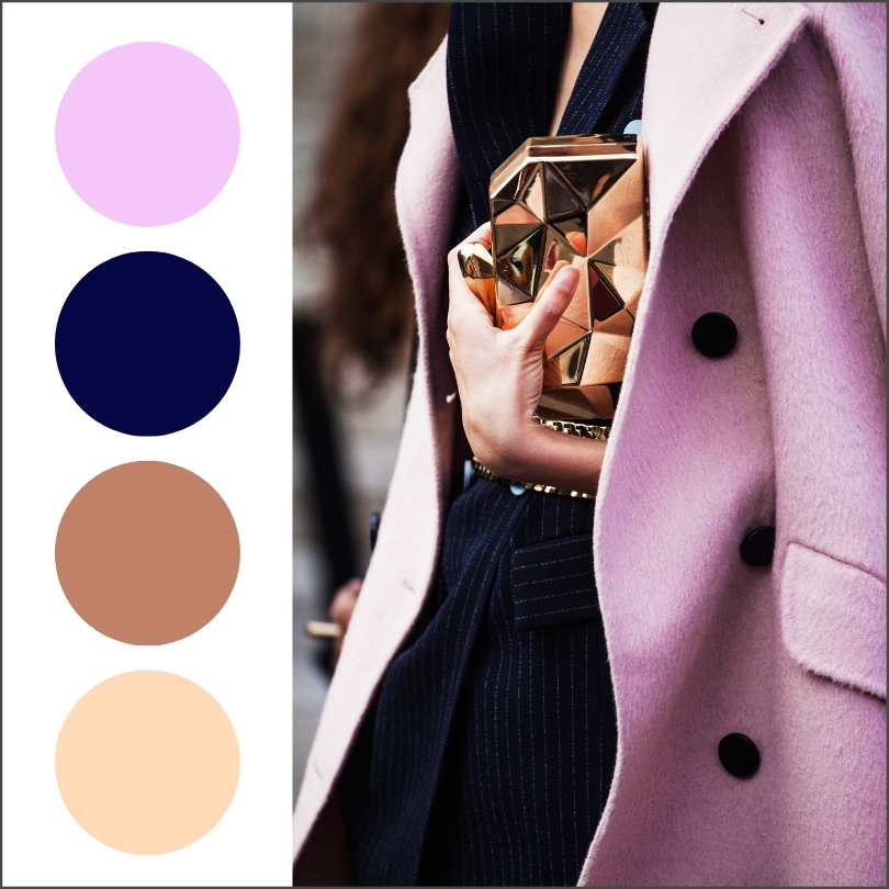 woman wearing navy pinstriped suit with lavender coat and gold handbag