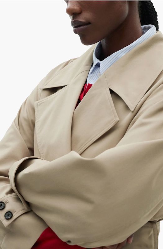 closeup of woman wearing beige trench coat over shirt and red knit