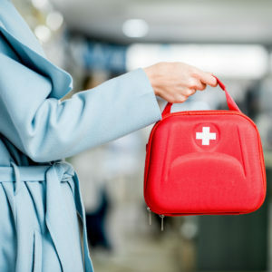 Woman in blue coat holding first aid kit