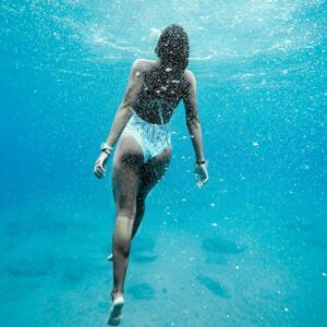 woman in swimsuit under water heading up to the surface