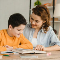Homeschool Style: Mother wearing chambray shirt over white tank top helps son with homework